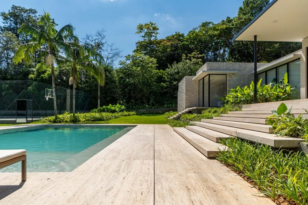 Residência contemporânea com piso e escadas em Travertino Romano ao redor da piscina